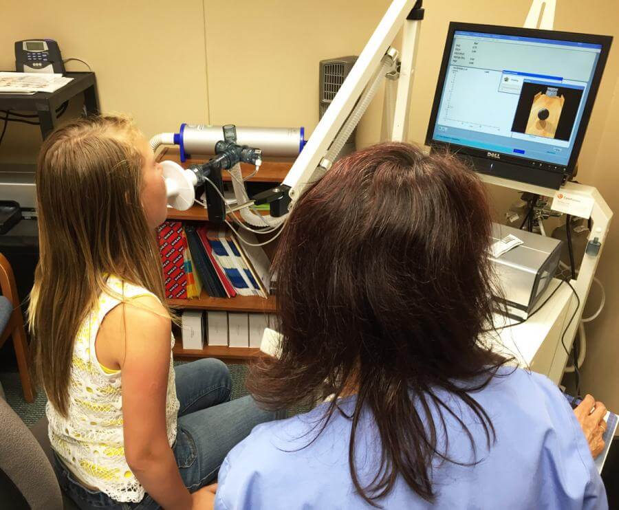 Brooklyn works with Jo Kreps to perform a breathing test called a Spirometry.