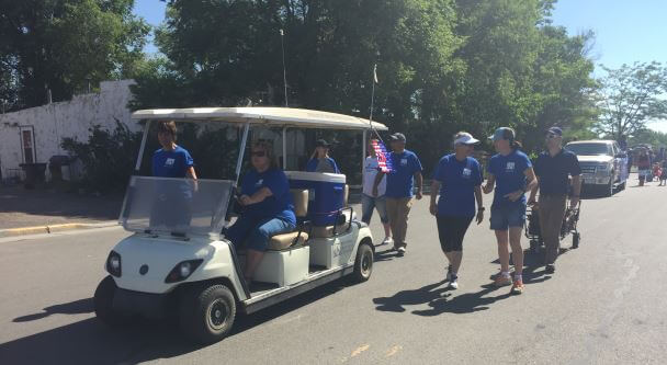 people walking & riding golf cart in parade