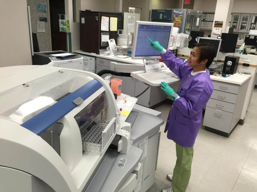 Woman wearing scrubs pointing at screen