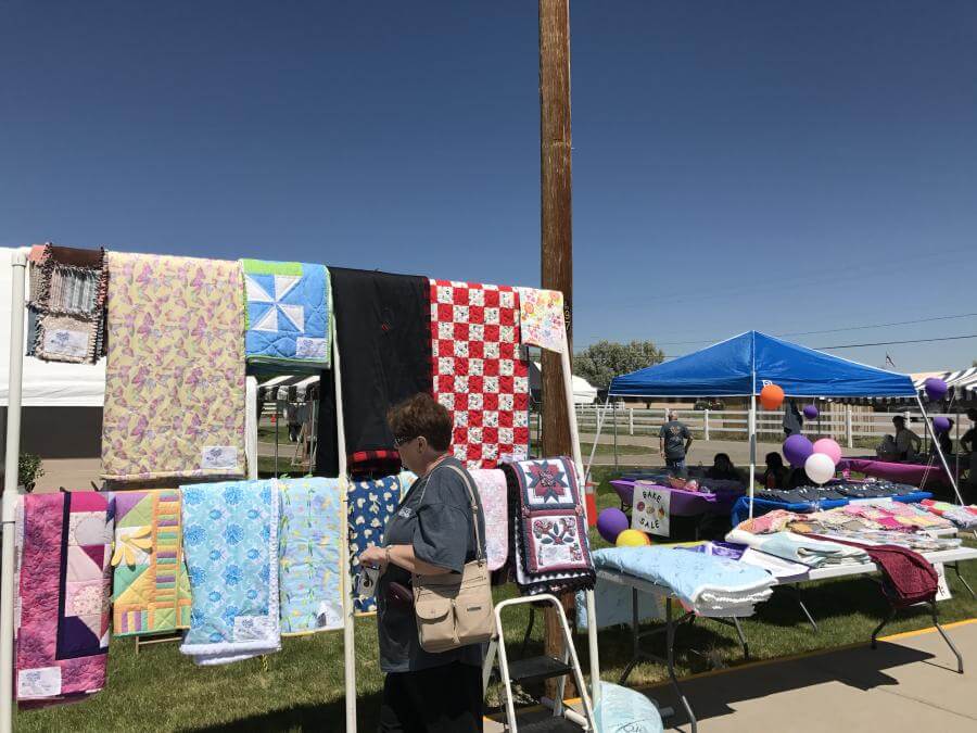 Racks display several colorful quilts available for auction at the event