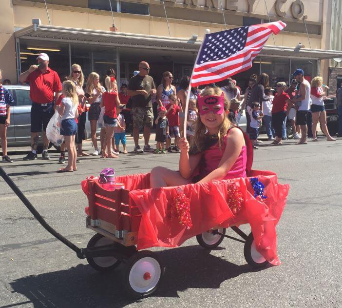 child in superhero costume in wagon in parade